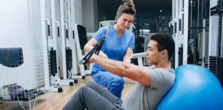 kinesiologist helps a mixed race man doing exercises to strengthen his back muscles. treatment of back pain using kinesitherapy.